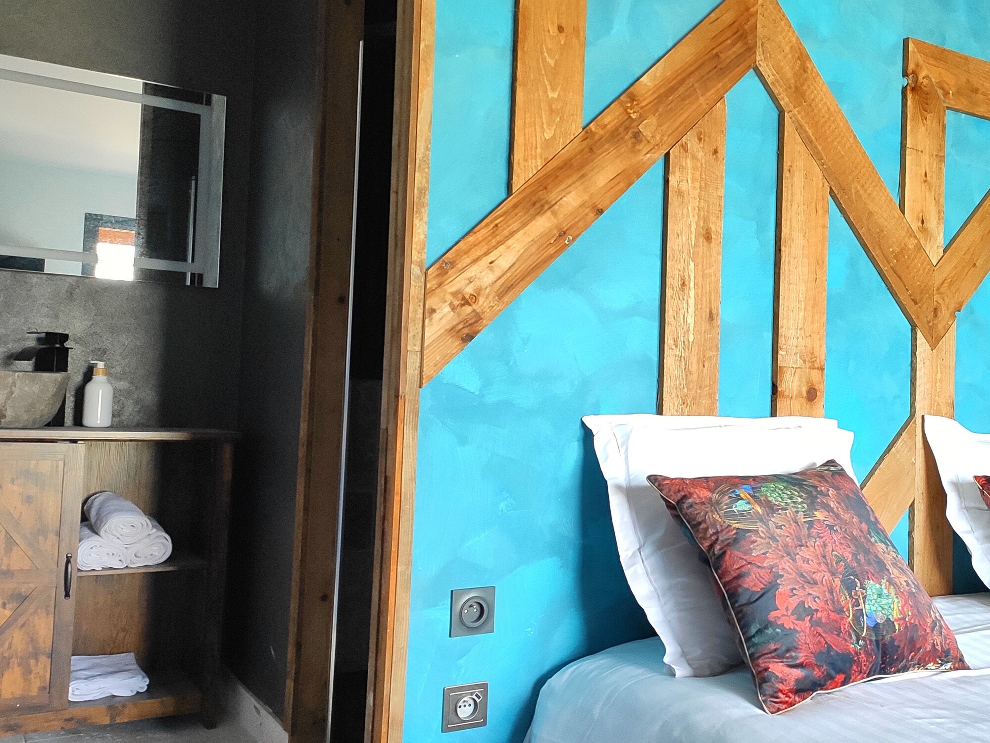 A bedroom with a wooden headboard, a bed with white bedding, and a colorful pillow.