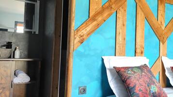 A bedroom with a wooden headboard, a bed with white bedding, and a colorful pillow.