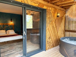 Quarto com porta de vidro deslizante para uma varanda, teto de madeira e hidromassagem.