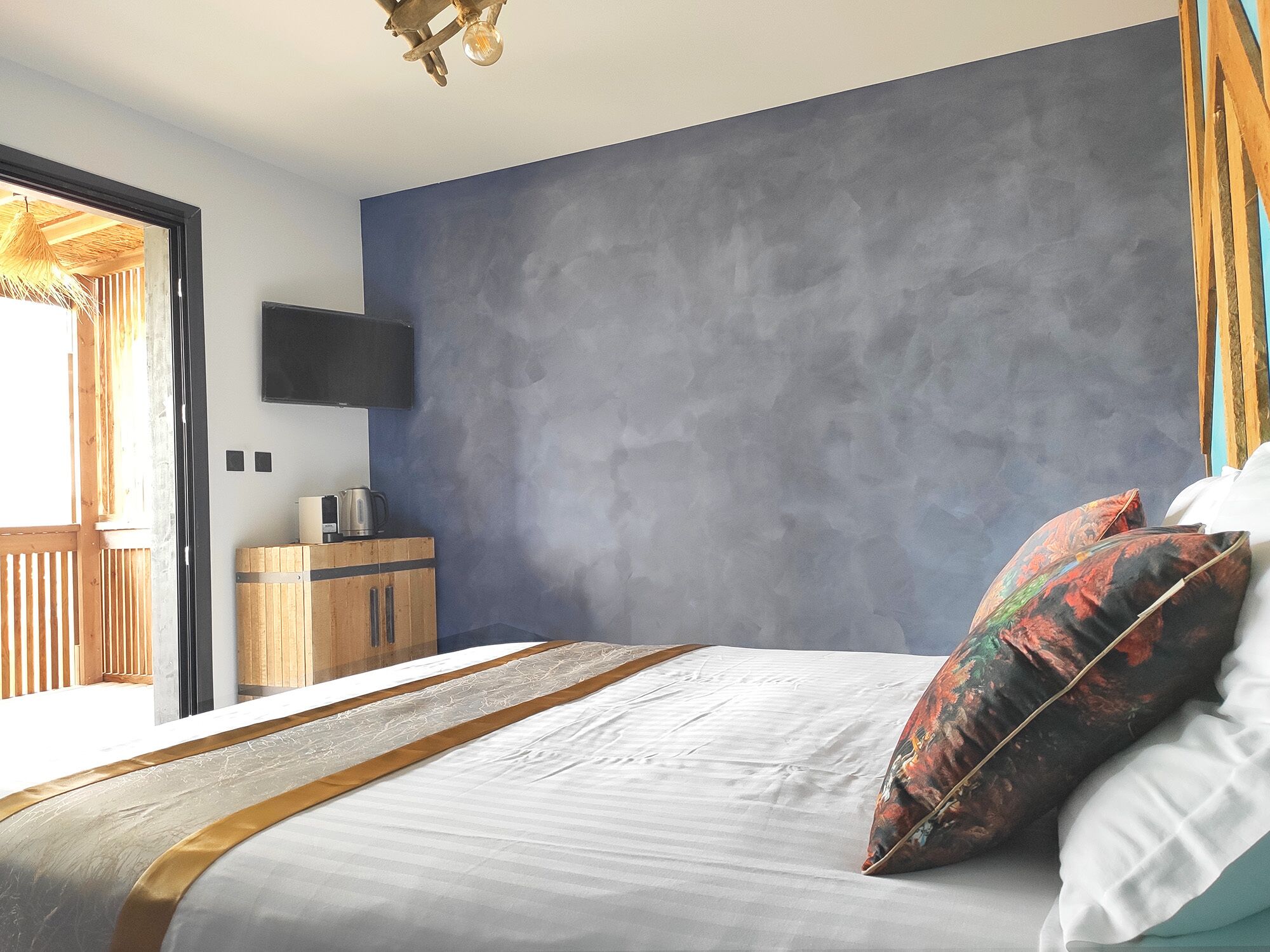 A bedroom with a bed, a TV mounted on the wall, and a wooden cabinet.