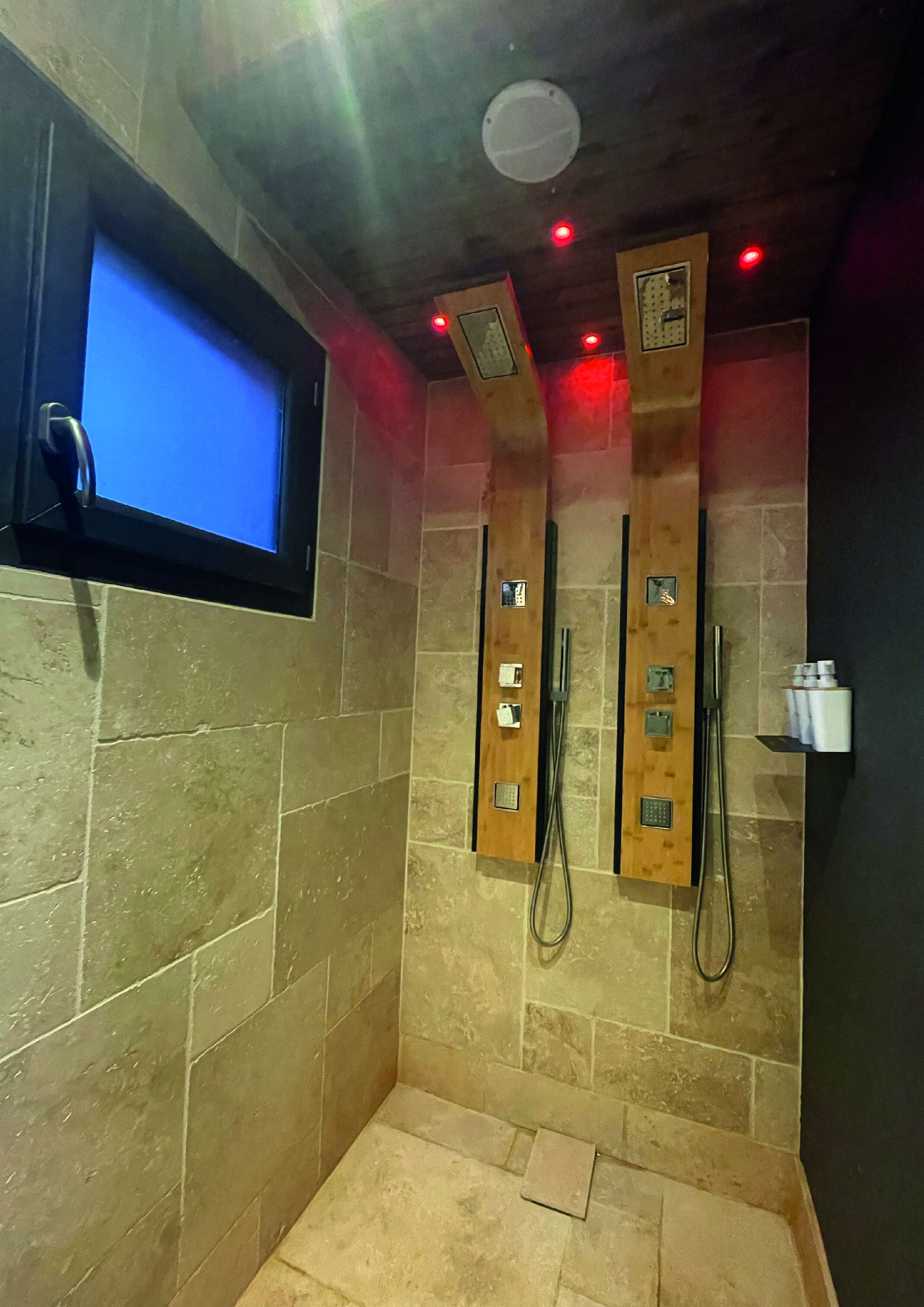 Zona de ducha con pantalla digital, paneles de madera y suelo de baldosas.