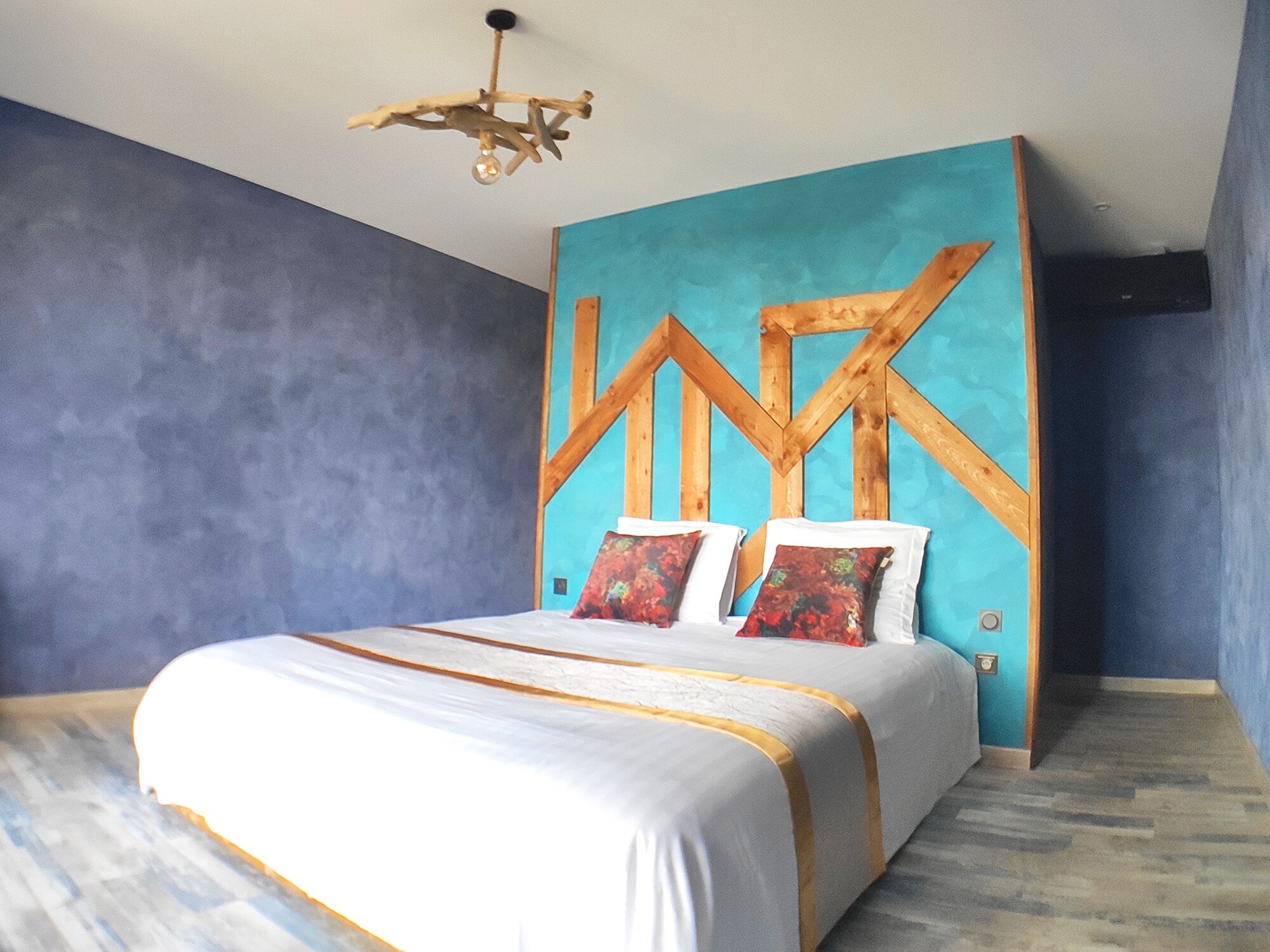A bedroom with a bed, a wooden headboard, and a ceiling light fixture.