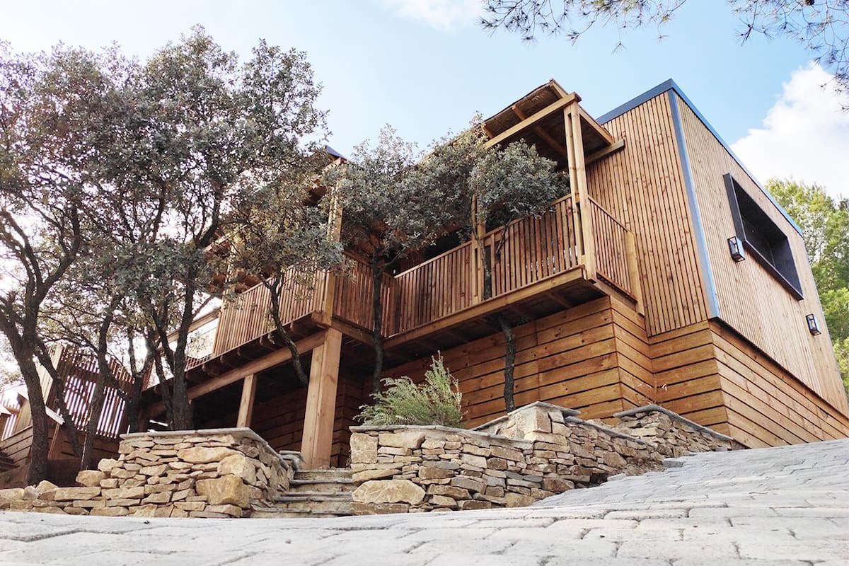 Une cabane en bois avec des fondations en pierre, des balcons en bois et un mur en pierre.