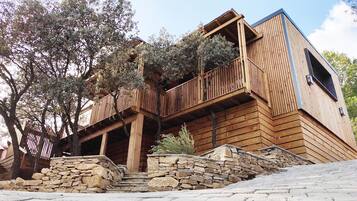 A wooden cabin with a stone foundation, wooden balconies, and a stone wall.