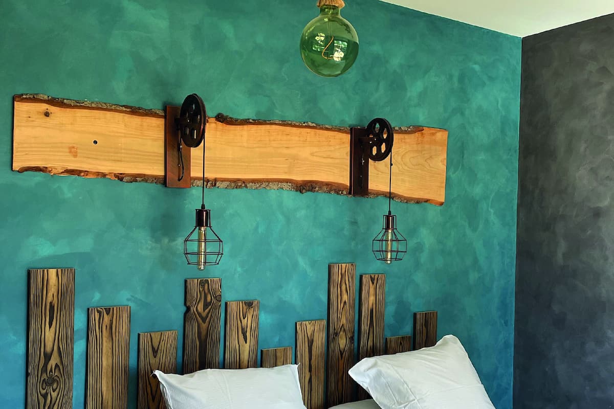 Un lit avec du linge de lit blanc, une tête de lit en bois et un mur de couleur turquoise.