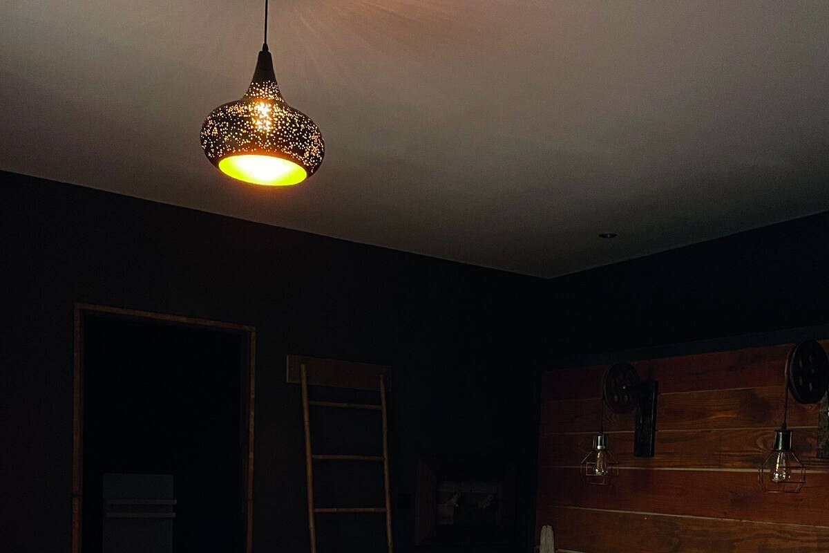 Une chambre avec un grand lit, une tête de lit en bois et un luminaire suspendu.