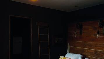 A bedroom with a large bed, wooden headboard, and a hanging light fixture.