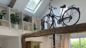 Amplia sala de estar con una mesa de comedor de madera, un sofá y una escalera que conduce a un nivel superior.
