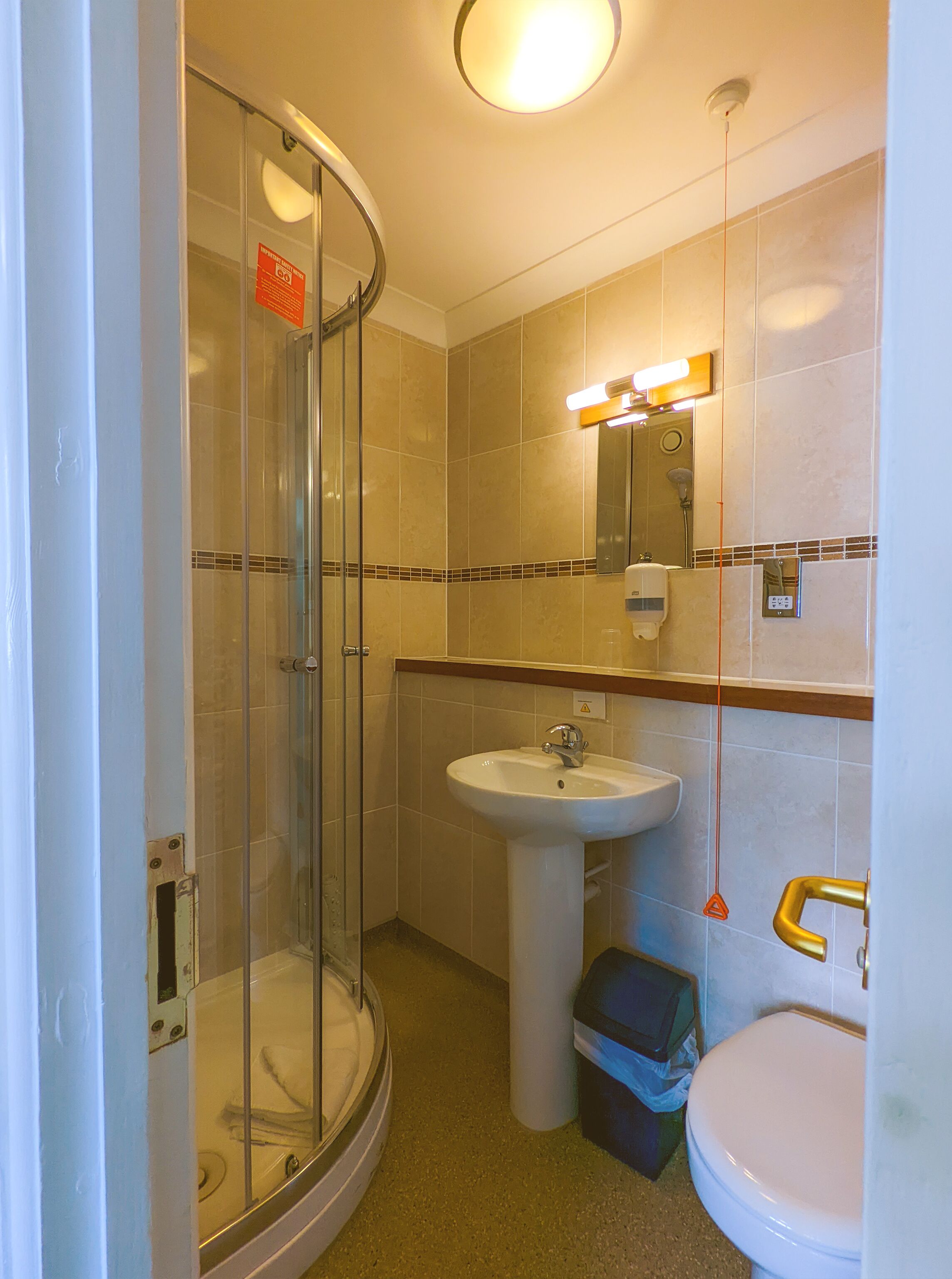 A bathroom with a glass shower enclosure, a sink, and a toilet.