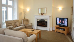 A living room with a fireplace, a television, and comfortable seating. - THE GROVE HOTEL (Bournemouth)