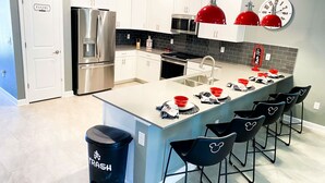 A modern kitchen with white cabinets, stainless steel appliances, and a central island with bar stools.