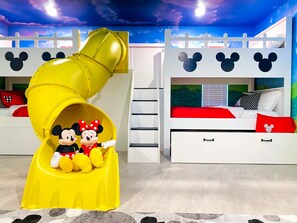 A children's play area with a yellow slide and Mickey Mouse-themed beds.