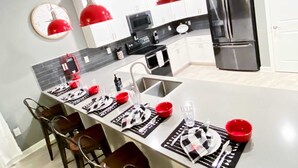 A modern kitchen with white cabinets, a black countertop, and a stainless steel refrigerator.