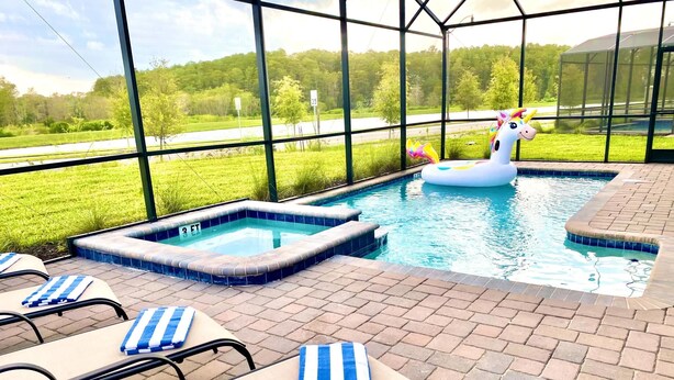 A swimming pool with a unicorn float, lounge chairs, and a view of a road and greenery.
