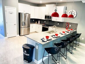 A modern kitchen with white cabinets, stainless steel appliances, and a central island with bar stools.