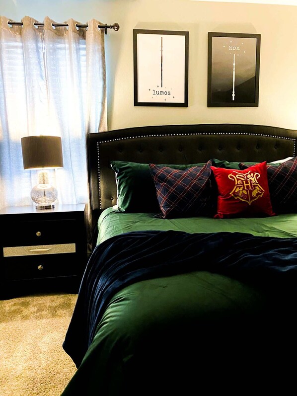 A bedroom with a bed, a nightstand, a lamp, and two framed pictures on the wall.