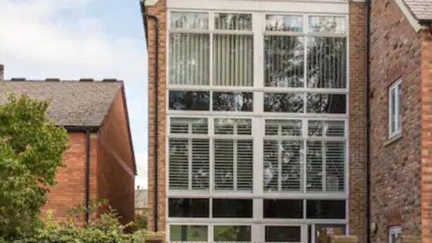 Un immeuble de deux étages doté d’une grande baie vitrée et d’une façade en briques.