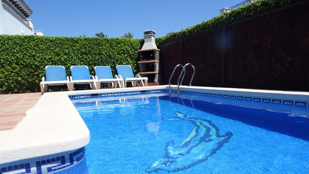 Ein Swimmingpool mit klarem, blauem Wasser, umgeben von weißen Liegestühlen und einer gefliesten Kante.