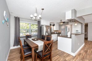 Una cocina moderna con armarios de madera, una isla central y una zona de comedor con una mesa y sillas.