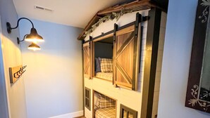 A narrow hallway with a wooden floor, a loft-style bed with a window, and a wall-mounted light fixture. - Heartwood♥ Cabin loft w/private HotTub, Hiking, Fishing, & Ziplines on 66 acres! (Floyd)