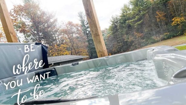 A hot tub with a motivational quote, surrounded by trees and wooden beams. - Heartwood♥ Cabin loft w/private HotTub, Hiking, Fishing, & Ziplines on 66 acres! (Floyd)