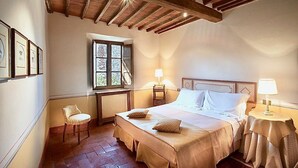 A bedroom with a wooden ceiling, a bed with white linens, a chair, a window, and a nightstand with a lamp. - CASA VISTA - Four Bedroom Villa, Sleeps 8 (Gaiole in Chianti)