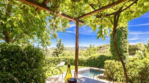 A table with a bottle of wine, a glass, and a plate of bread in a garden setting with a pool and a view of hills. - CASA VISTA - Four Bedroom Villa, Sleeps 8 (Gaiole in Chianti)