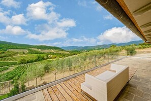A balcony with a view of vineyards and hills.