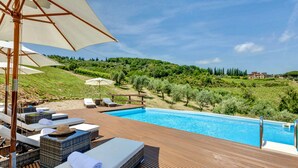 A poolside area with lounge chairs and umbrellas, surrounded by greenery and hills. - VILLA CHIANTI ROSSO - Four Bedroom Villa, Sleeps 9 (Greve in Chianti)
