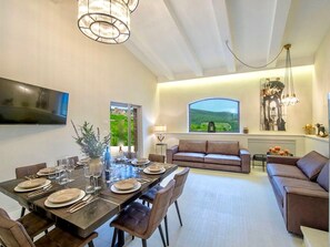 Una sala de estar moderna con comedor, un sofá y un televisor montado en la pared.