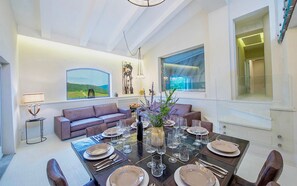 A dining area with a table set for six, a sofa, and a view of the outdoors.
