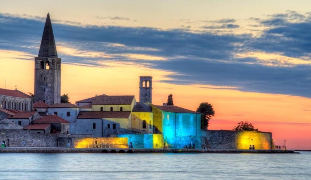 A historic waterfront cityscape with a prominent church tower and a fortified wall.