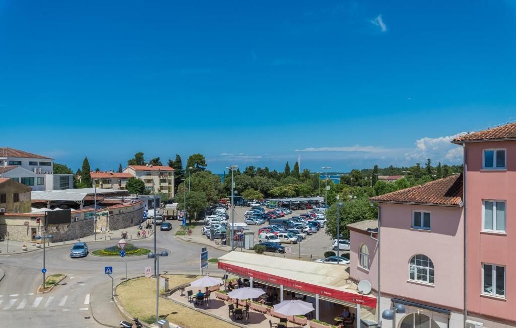A parking lot with multiple cars, a gas station, and buildings with red-tiled roofs.