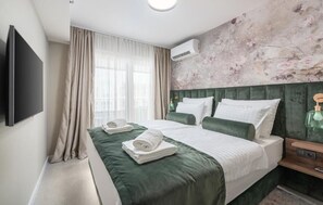 A hotel room with a bed, a flat-screen TV, a nightstand, and a wall-mounted air conditioner. - Apartment Val di Sole II (Porec)
