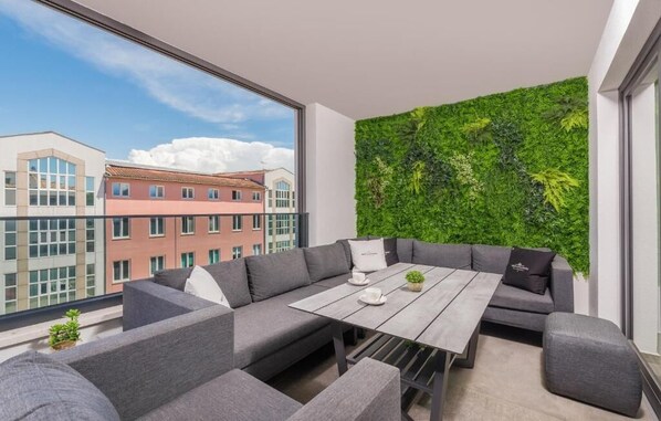A modern living room with a large window, grey sofa, and a green vertical garden wall. - Apartment Val di Sole II (Porec)