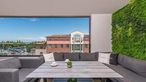 A modern outdoor seating area with a view of a building and parking lot. - Apartment Val di Sole II (Porec)