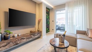 A modern living room with a flat-screen TV, a marble console, a sofa, and a glass table with a bottle and glass. - Apartment Val di Sole II (Porec)