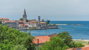 Un pueblo costero con edificios históricos, una torre destacada y un paseo marítimo.