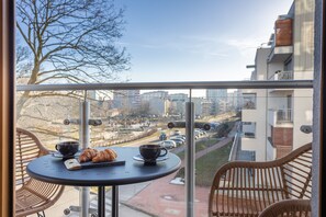 Un balcon avec une table, des chaises et un croissant.