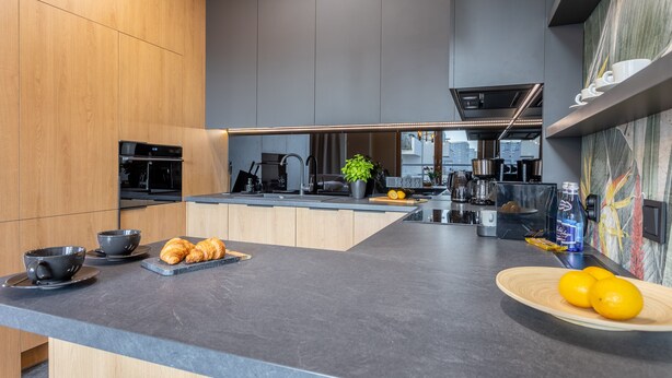 Une cuisine moderne dotée d’un grand îlot central, d’appareils électroménagers intégrés et offrant une vue sur la ville.