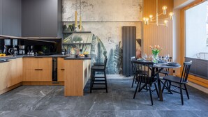 Une cuisine moderne dotée d’un îlot central, de meubles en bois et d’un coin repas avec des chaises noires et une table dressée pour six personnes.