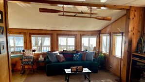 Un intérieur de chalet chaleureux avec un canapé vert, des murs en bois et une vue sur un quai.