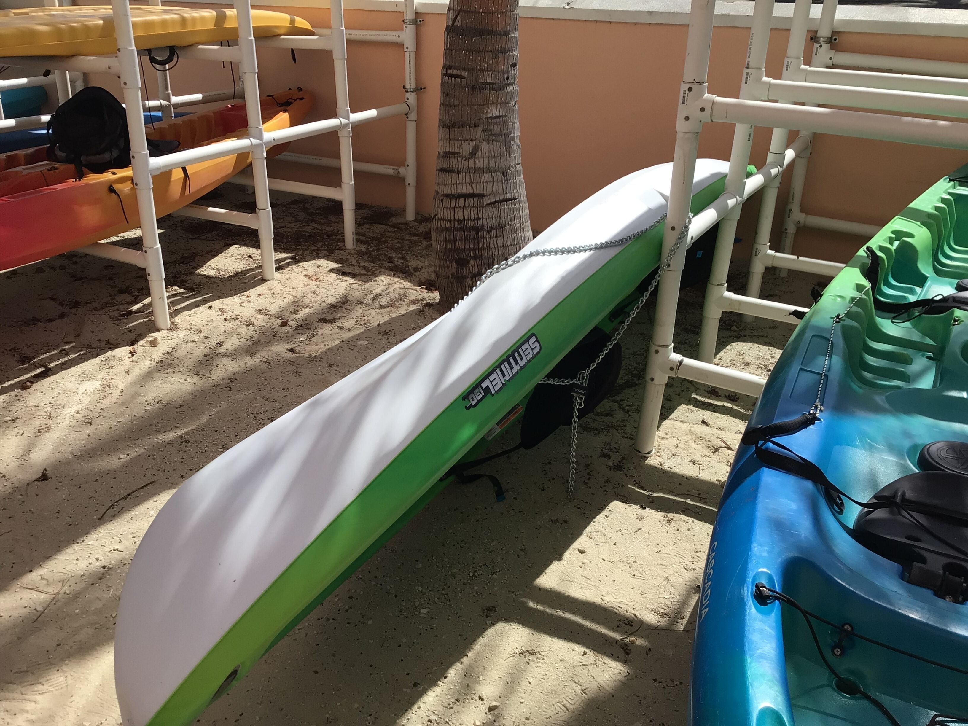 A kayak and a surfboard leaning against a white metal structure.