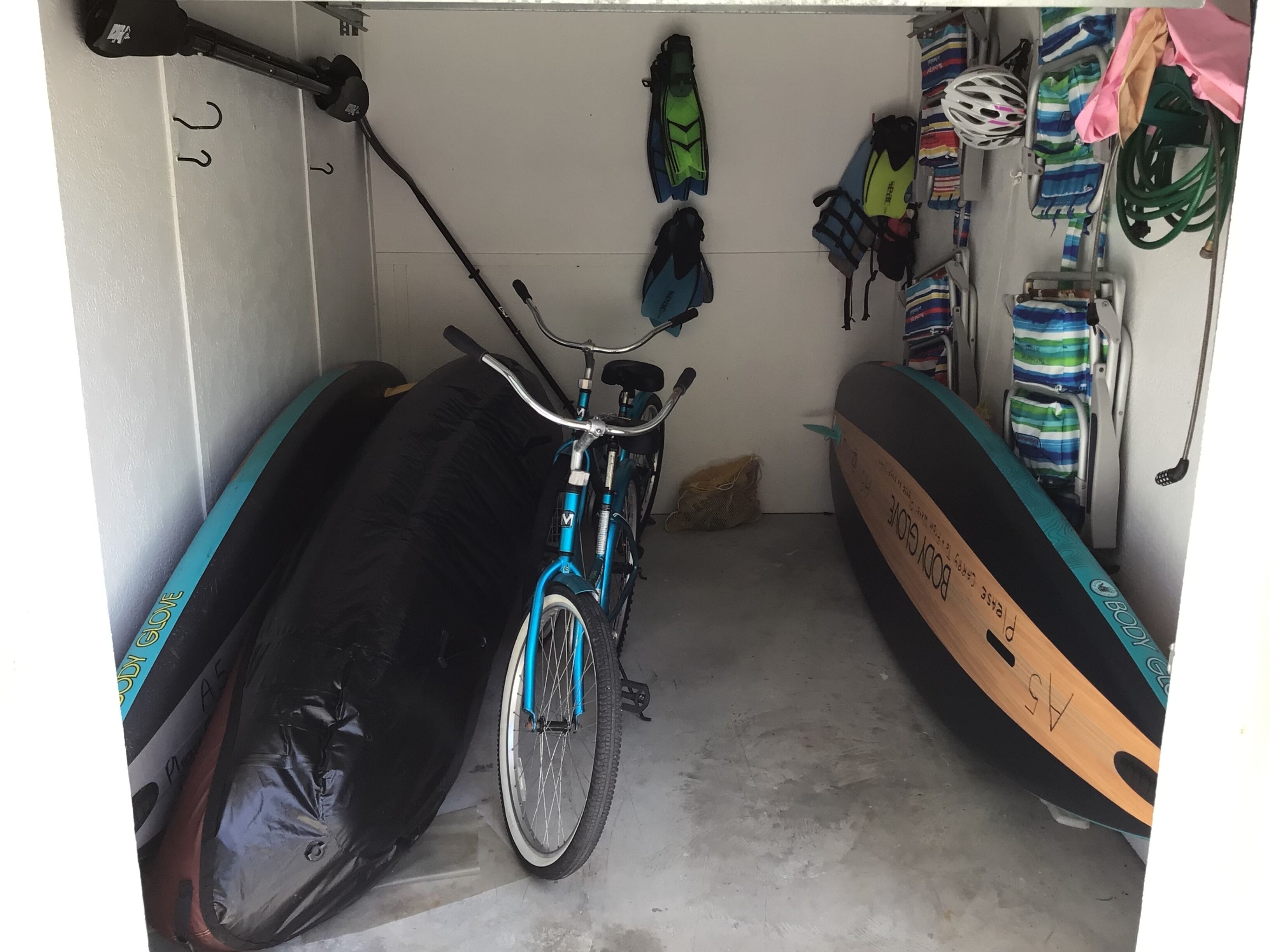 Un vélo dans un garage, avec une planche de surf et un kayak.