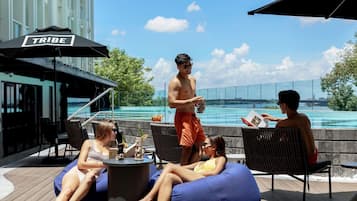 A poolside area with lounge chairs, a table, and a sign labeled 'TRIBE'.