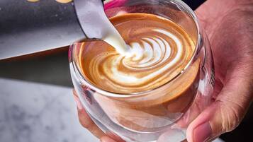 Una persona sosteniendo una taza de café con un dibujo de arte latte.