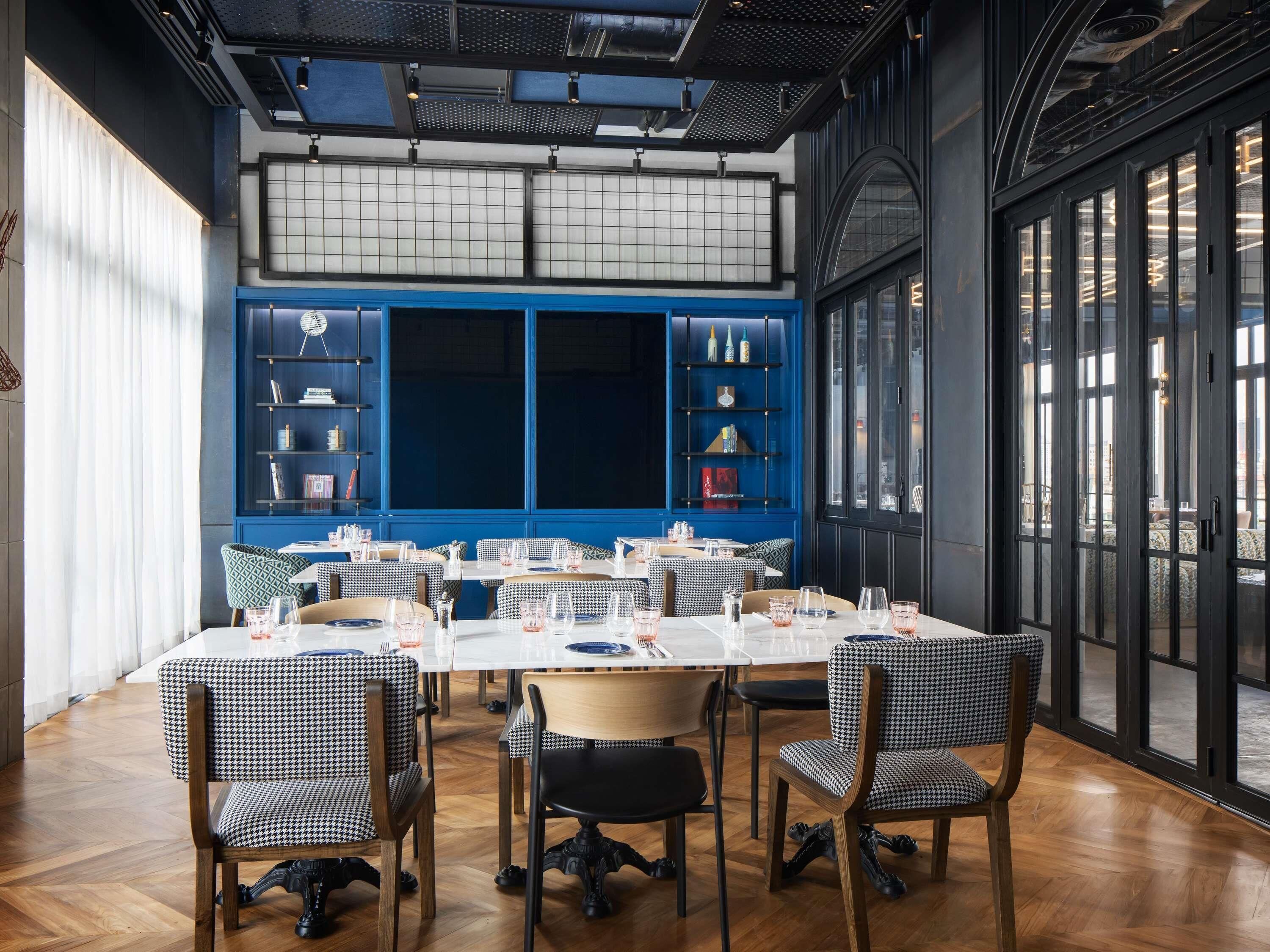 A dining area with checkered chairs, a large table, and blue shelving units with books and decorative items.