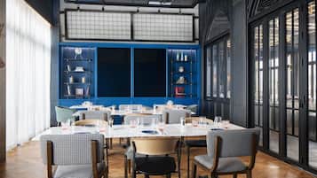 A dining area with checkered chairs, a large table, and blue shelving units with books and decorative items.