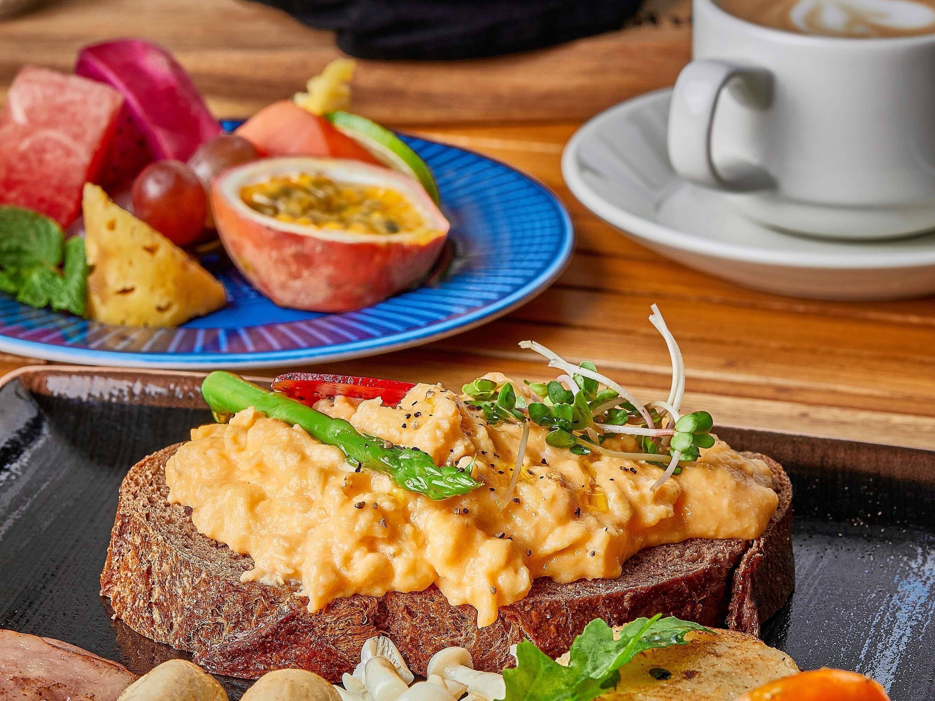 A meal with bread, scrambled eggs, and vegetables on a plate.