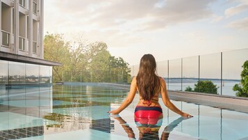 Una piscina al aire libre, sombrillas, sillones reclinables de piscina